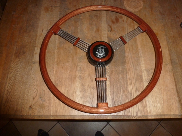 The restored steering wheel made according to the circular wrapping method out of Mahogony slats. Logo in the middle is cast in epoxy